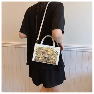 Dettaglio della borsa bianca con paillettes dorate e manico elegante sulla modella