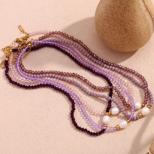 Multi-layer purple beaded necklace with freshwater pearls and gold accents on flat lay