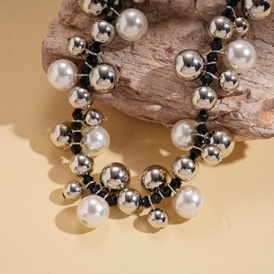 Detailed close-up of retro necklace with large silver beads and white pearls on wood