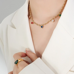 Golden rope chain necklace with colorful heart zircons and green gemstone ring set on model