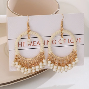 Detailed view of bohemian hoop earrings with woven cotton cord and gold chain tassels