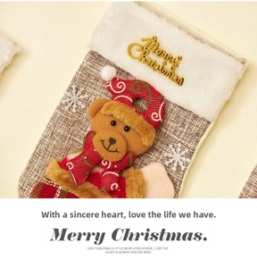 Close-up of linen Christmas stocking featuring 3D plush bear and golden Merry Christmas text
