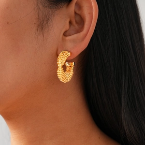 Close-up of golden 24k plated twisted C-shape earrings worn by a model in detail