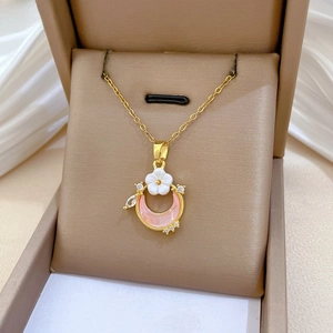 Detailed close-up of crescent moon necklace with pink stone and white flower accents