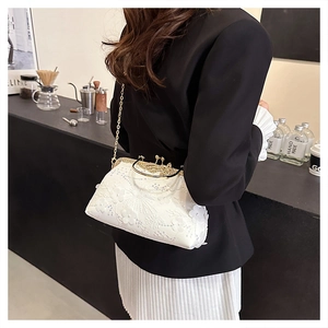 Detail of white mesh clutch with floral embroidery and sequins on gold chain strap