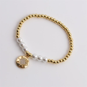 Détail d'un bracelet perlé avec perles dorées, perles et un pendentif étoile boussole