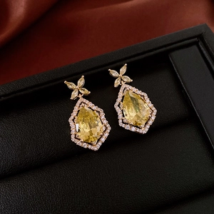 Vue macro des boucles d'oreilles fleur dorées avec zircon jaune goutte en boîte noire