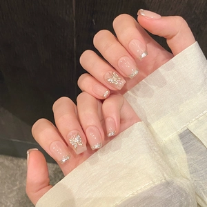 Dettaglio unghie finte rosa nude con punte glitter argento e decorazione a farfalla 3D