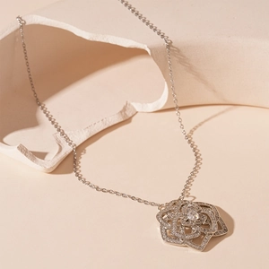Macro shot of a silver floral pendant with zircon petals on a modern ceramic display