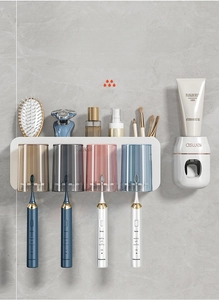 Detail of wall-mounted toothbrush holder with four colored cups and automatic toothpaste dispenser
