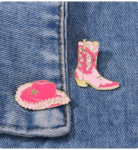 Pink western enamel pin set with cowboy boot and hat on blue denim background