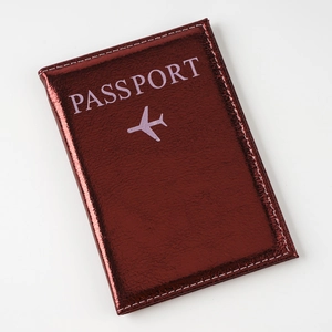 Detail of wine red metallic passport cover with embossed airplane icon and clean stitching