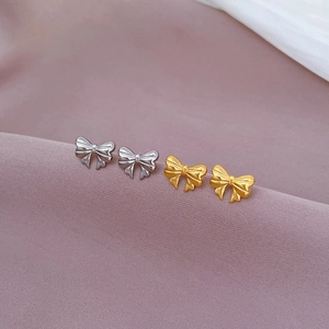Minimalist titanium steel bow earrings in gold and silver set on pink fabric