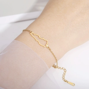 Close-up of golden stainless steel Lebanon map pendant on a wrist with adjustable chain