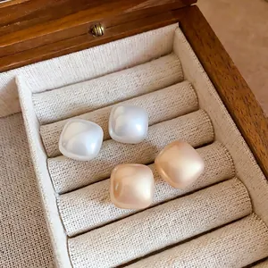 Square pearl stud earrings set in white and champagne gold with warm satin finish
