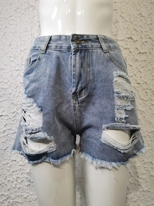 Détail d'un short en jean bleu clair à taille haute avec déchirures et bords effilochés