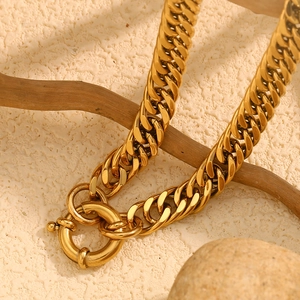 Close-up of a gold-plated chunky Cuban chain necklace with a large OT spring clasp