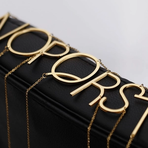 Colliers pendentifs alphabet en acier inoxydable doré O à T sur présentoir noir