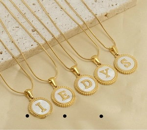 Macro shot of 18K gold plated stainless steel snake chain necklaces with shell initial pendants