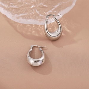 Minimalist silver teardrop hoop earrings with high-polished mirror finish on beige fabric
