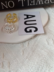 Dettaglio di anelli a sfere minimalisti in oro e argento su sfondo bianco testurizzato