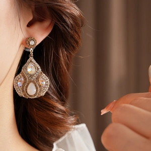 Gros plan de boucles d'oreilles vintage dorées avec cristaux en goutte sur mannequin