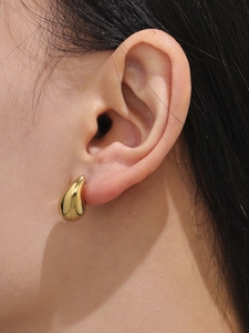 Close-up of 18k gold plated hollow teardrop earrings worn on ear with polished finish