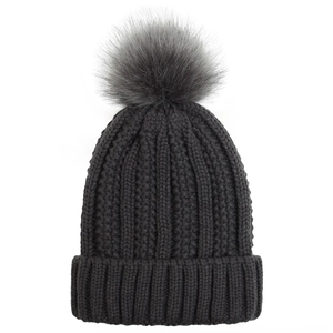 Close-up of thick dark grey cable knit beanie with large faux fur pompom and folded cuff