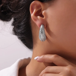 Silver oval hoop earrings with textured metallic finish on model in minimalist style