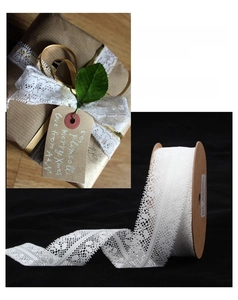 Macro detail of 28mm white floral lace ribbon roll for elegant gift wrapping