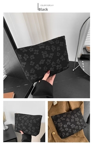 Detail of black embossed floral clutch showing 3D texture and top zipper closure
