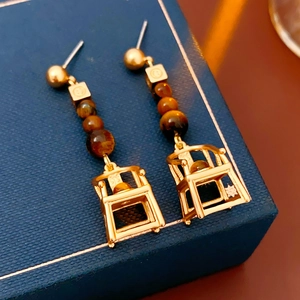 Detail of vintage gold-tone drop earrings featuring tiger eye beads in cage design