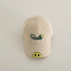 Detailed embroidery of a green Smile text and yellow smiley face on a beige cotton cap