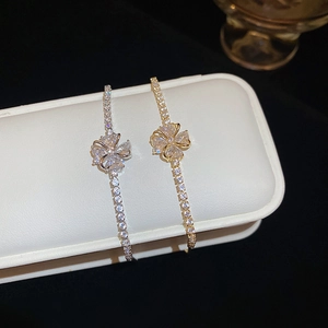 Detail of silver and gold flower bracelets with cubic zirconia on a white leather stand