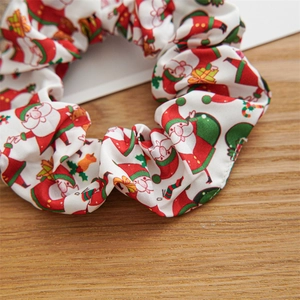 Detailed view of Christmas themed hair scrunchie with Santa and gift patterns on wood