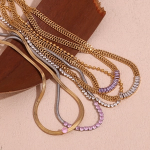 Detail of 18K gold plated necklaces with pink and purple zircon on wooden display