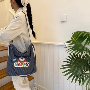 Detailed close-up of a blue striped canvas tote bag with a colorful happy dog embroidery