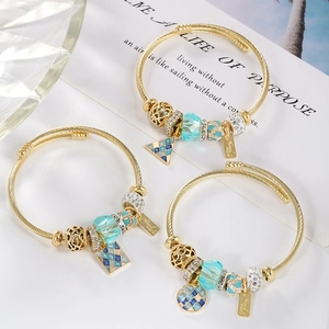 Gold spiral open bracelet with celestial mosaic starburst pendants and blue crystals
