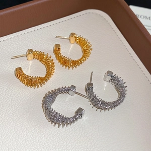 Twisted C-shaped gold and silver hoop earrings with metallic coil design on white tray