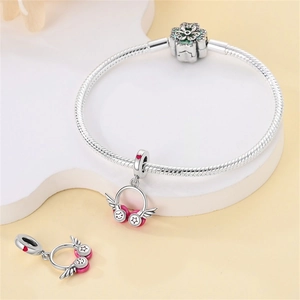 Detail view of silver snake chain bracelet with pink headphone charm and floral clasp