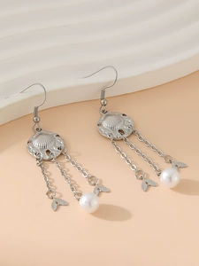 Detailed view of silver fishtail tassel earrings with engraved shell pattern and pearls