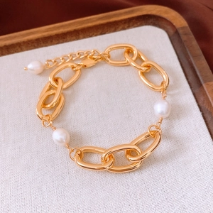 Detailed macro view of 18k gold-plated chain bracelet with lustrous white pearls