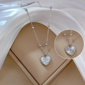 Detailed macro view of heart pendant necklace with white mother of pearl and silver beads