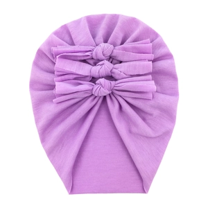 Detail of soft purple baby cotton knit hat featuring three cute bows on a white background