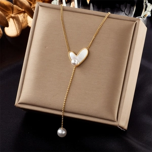 Close-up of double-layer necklace with heart and pearl pendant on golden box