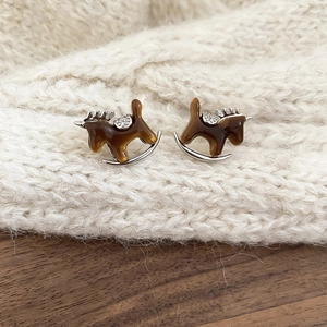 Macro shot of rocking horse stud earrings with amber resin and sparkling zircon stones