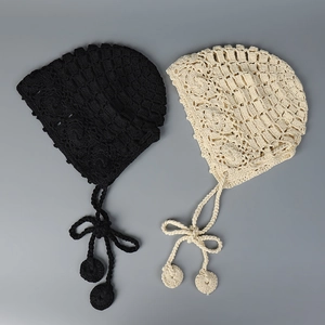 Détail de bonnets en crochet faits main en noir et crème avec de longs glands pompons