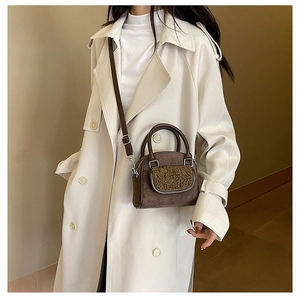 Brown vintage plush crossbody bag detail on model wearing a classic beige trench coat