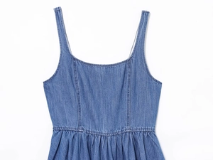 Dettaglio di abito in denim blu con pieghe in vita e texture lavata morbida