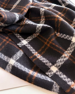 Detailed macro view of soft plaid cashmere-like fabric texture with fringe details